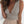 Vrouw in beige top met diepe V-hals en geplooide taille, gecombineerd met een lichte rok. Stijlvolle zomermode, casual chique outfit.