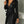 Zwarte leren jurk met diepe V-hals, ritssluiting en tailleband, gedragen door een vrouw. Perfect voor avondkleding en modieuze gelegenheden.