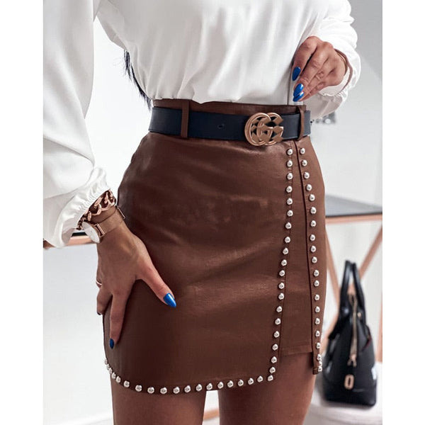 Vrouw in witte blouse en bruine leren rok met pareldetails, zwarte riem met gouden gesp, blauwe nagellak, modieuze outfit, stijlvolle accessoires.