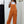 Vrouw in oranje tuinbroek en witte T-shirt, casual mode, buiten, witte muur, trendy dameskleding, comfortabele outfit, sneakers, lente stijl.