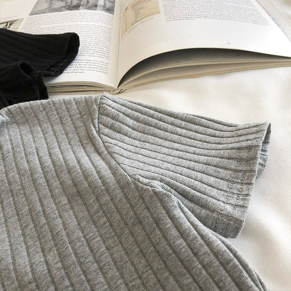 Grijs geribd T-shirt op een open boek, minimalistisch design, comfortabele casual mode, katoenen stof, trendy dameskleding, stijlvolle outfit.