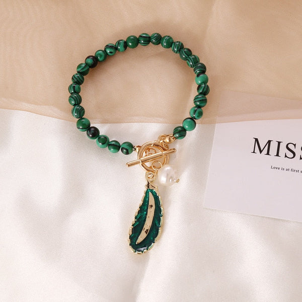 Groene malachiet armband met goudkleurige sluiting en hanger, elegante sieradenaccessoire, perfect voor modieuze dames, luxe uitstraling.