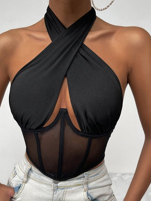 Zwarte haltertop met kruisbanden en doorschijnend mesh korset, gedragen door model. Trendy damesmode, sexy en stijlvol ontwerp.