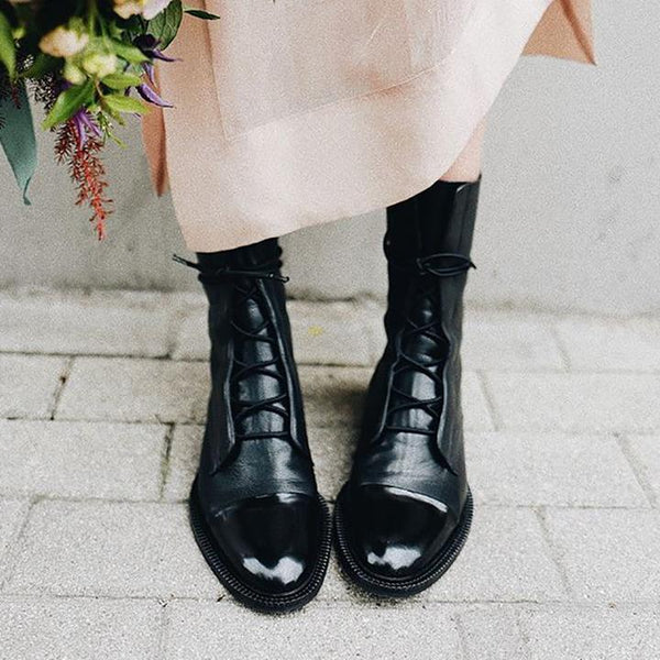 Zwarte leren veterlaarzen voor dames op stoeptegels, stijlvolle en modieuze schoenen, perfect voor herfst- en winteroutfits.
