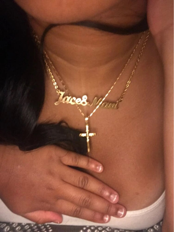 Gouden ketting met kruis hanger en naamplaatje, gedragen door vrouw. Stijlvolle sieraden, persoonlijke accessoires, modieuze kettingen.