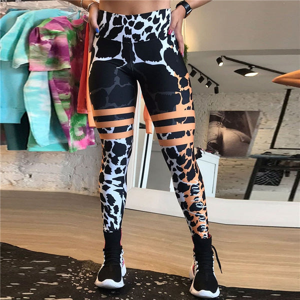 Dames sportlegging met koeienprint en oranje strepen, fitnesskleding in moderne boetiek, trendy en comfortabel voor workouts.