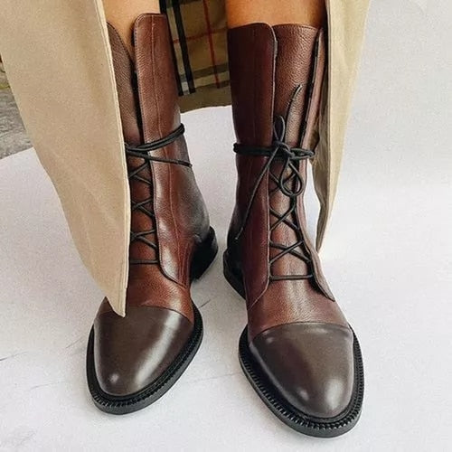 Bruine leren veterlaarzen voor dames, stijlvolle herfstmode, close-up. Elegante enkellaarzen met zwarte veters en stevige zolen.