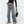 Vrouw draagt HOUZHOU Y2k wijde jeans met zijstrepen en veterdetails, gecombineerd met zwarte top en tas. Vintage baggy denim stijl.