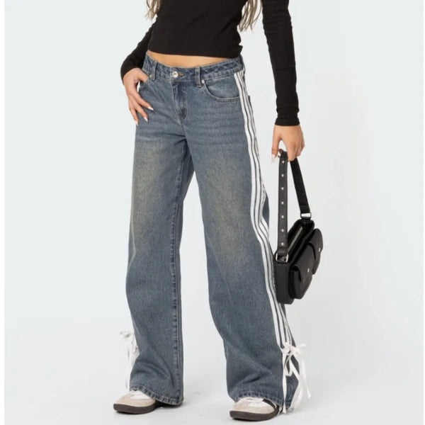 Vrouw draagt HOUZHOU Y2k wijde jeans met zijstrepen en veterdetails, gecombineerd met zwarte top en tas. Vintage baggy denim stijl.