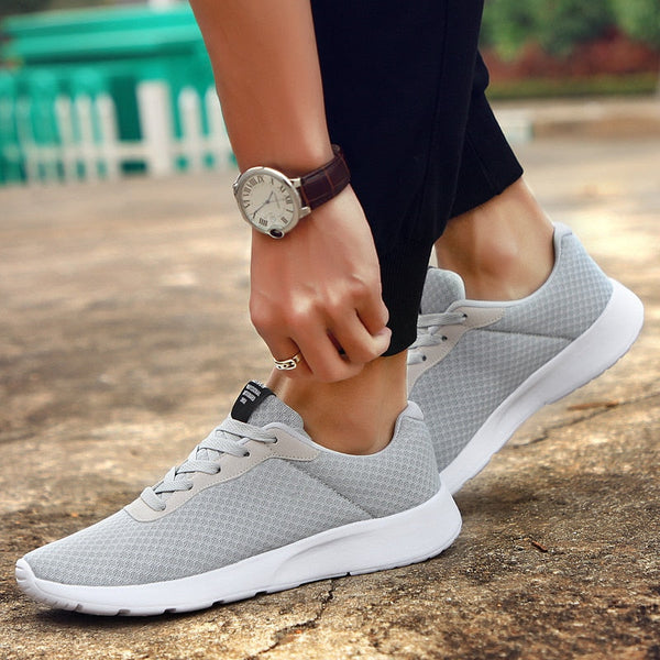Grijze sportschoenen voor heren, ademend mesh, comfortabele pasvorm, ideaal voor hardlopen en wandelen. Stijlvolle sneakers op een buitenlocatie.