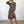 Vrouw in modieuze luipaardprint jurk met lange mouwen en split, poseert in minimalistisch interieur. Trendy damesmode, elegante stijl.