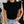 Vrouw in zwarte mouwloze top met ruches, hoge hals, gecombineerd met lichtblauwe jeans met knopen. Modieuze casual outfit, trendy dameskleding.