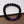 Zwart lavasteen armband met paarse pijlvormige kralen, stijlvol en modern, liggend op een bruine ondergrond naast een tablet.