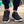Zwarte sportschoenen met witte zolen, gedragen door een persoon op een stoep. Comfortabele sneakers voor hardlopen en dagelijks gebruik.