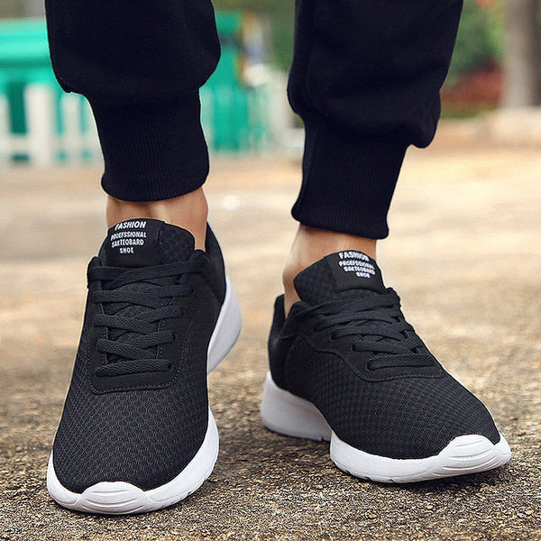 Zwarte sportschoenen met witte zolen, gedragen door een persoon op een stoep. Comfortabele sneakers voor hardlopen en dagelijks gebruik.