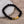 Zwarte lavasteen armband met gouden pijlvormige accenten op houten achtergrond, stijlvolle sieradenaccessoire voor mannen en vrouwen.