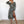Vrouw in modieuze luipaardprint jurk met lange mouwen en split, poseert in minimalistische kamer. Trendy damesmode, elegante stijl.