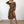Vrouw in modieuze luipaardprint jurk met lange mouwen en split, poseert in minimalistische kamer. Trendy damesmode, dierenprint, elegante stijl.