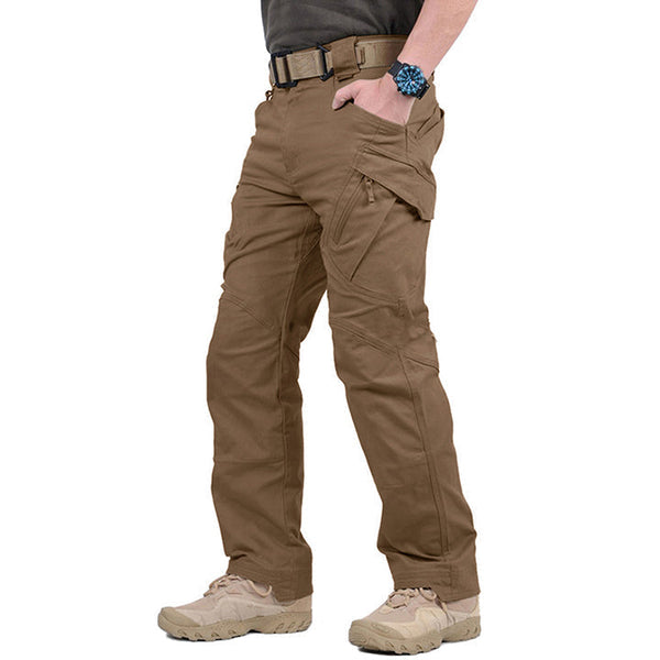 Man in bruine tactische broek met meerdere zakken, stevige riem en beige wandelschoenen. Ideaal voor outdooractiviteiten en survival.