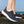 Donkergrijze ademende sneakers voor heren op rotsachtige ondergrond, ideaal voor wandelen en hardlopen. Comfortabele sportschoenen met witte zool.