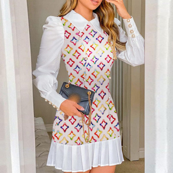 Vrouw in witte jurk met kleurrijk patroon en plissérok, houdt een zwarte handtas vast. Modieuze dameskleding, elegante outfit, trendy stijl.