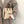 Vrouw met beige teddy schoudertas en bruine leren handvatten, gekleed in grijze jas. Modieuze winteraccessoires, trendy damesmode.