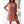 Vrouw in roze polkadot zomerjurk met korte mouwen en strikceintuur, staand in lichte woonkamer. Trendy damesmode, casual elegantie.