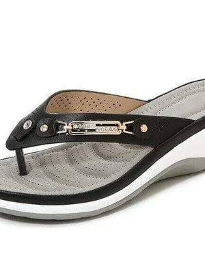 Zwarte dames teenslipper met sleehak, comfortabel voetbed en metalen decoratie. Perfect voor zomerse casual outfits en stranduitjes.