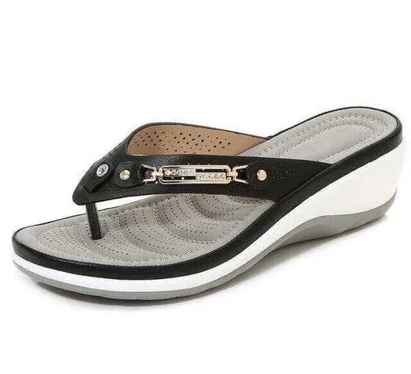 Zwarte dames teenslipper met sleehak, comfortabel voetbed en metalen decoratie. Perfect voor zomerse casual outfits en stranduitjes.