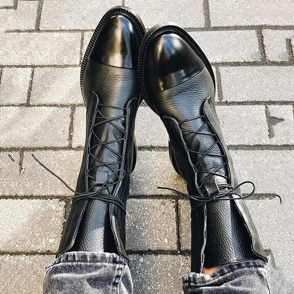 Zwarte leren veterlaarzen op stoeptegels, stijlvolle damesmode, trendy schoenen, casual outfit, herfst- en wintermode, comfortabele pasvorm.