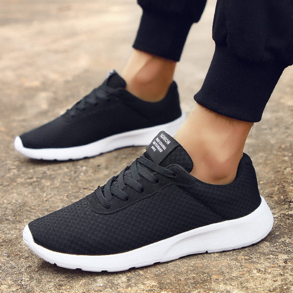 Zwarte sportschoenen voor heren met witte zool, ademend mesh materiaal, ideaal voor hardlopen en casual gebruik. Comfortabele en stijlvolle sneakers.