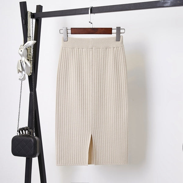 Beige gebreide rok met hoge taille en split, hangend aan een zwarte kledingrek. Modieuze dameskleding, ideaal voor herfst- en winteroutfits.