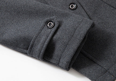 Donkergrijze wollen jas met knoopsluiting en opgerolde mouw, stijlvolle wintermode, hoogwaardige stof, close-up detail.