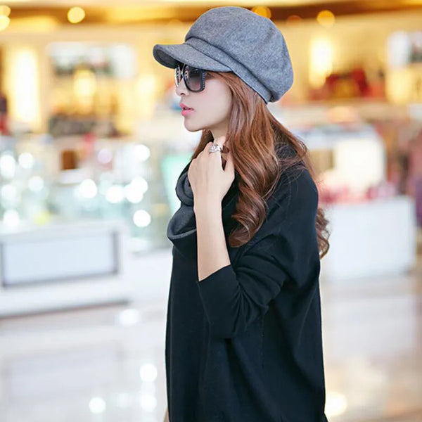 Vrouw met grijze pet en zonnebril in winkelcentrum, modieuze herfstkleding, casual zwarte trui, trendy accessoires, winkelachtergrond.