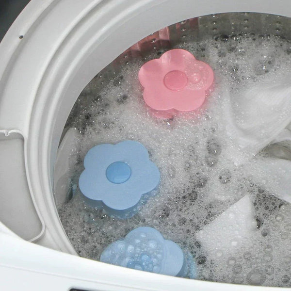 Roze en blauwe wasmachine pluizenfilters in bloemvorm drijven in sop in een wasmachine. Handige wasaccessoires voor pluizenverwijdering.