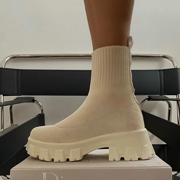 Beige enkellaars met dikke zool op stoel, trendy damesmode, comfortabele soklaars, modern design, herfst/winter 2023 schoenen.