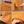 Geribbelde okergele rok, zachte stof, elastische tailleband, splitdetail, close-up textuur. Perfect voor herfstmode en comfortabele stijl.