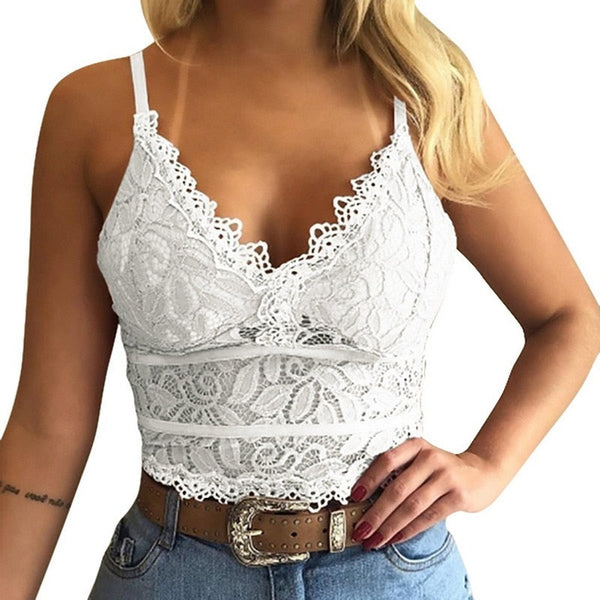Vrouw in witte kanten crop top met spaghettibandjes, gecombineerd met blauwe jeans en bruine riem. Modieuze zomerse outfit, casual stijl.