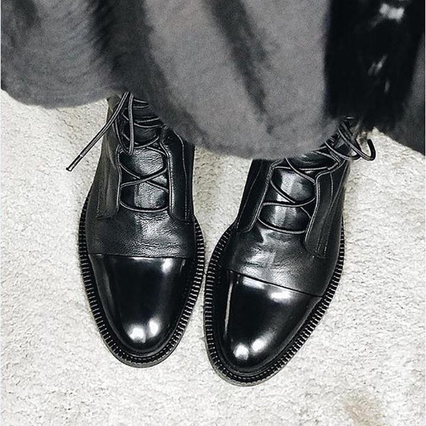 Zwarte leren herenschoenen met veters, glanzende afwerking en gestikte zolen op een lichte vloer. Stijlvolle, formele schoenen voor herenmode.