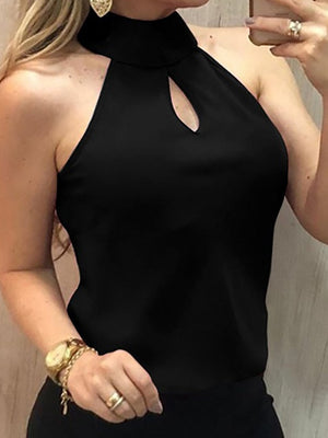 Vrouw in zwarte haltertop met sleutelgatdetail, gouden sieraden en smartphone. Modieuze dameskleding, elegante avondoutfit, trendy accessoires.