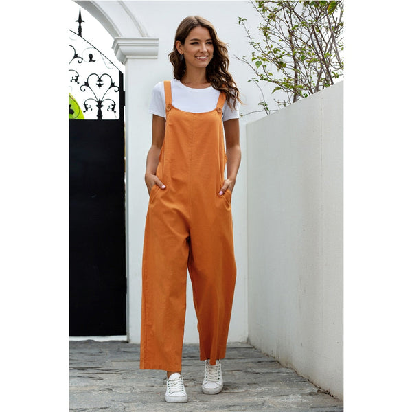 Vrouw in oranje tuinbroek en wit T-shirt, wandelend op stenen pad. Casual mode, zomerse outfit, comfortabele kledingstijl, witte sneakers.