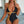 Vrouw in stijlvolle zwarte en gouden badpak met diepe halslijn, zittend op een bank. Trendy badmode, zomeroutfit, strandkleding.