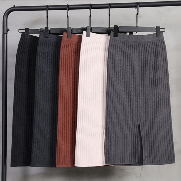 Vijf geribbelde midi-rokken in zwart, bruin, beige en grijs hangen aan een kledingrek. Modieuze damesrokken, winterkleding, casual stijl.