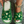 Groene pluche pantoffels met gouden kerstmotieven, gedragen door een persoon met een gouden armband. Perfect voor wintercomfort en feestelijke stijl.
