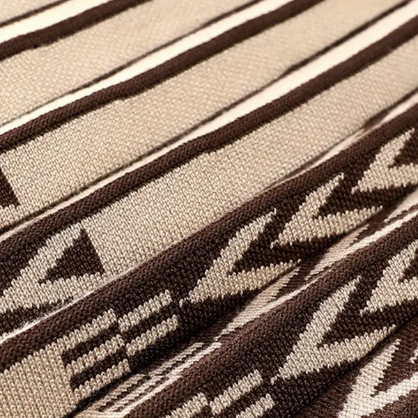 Bruin-beige gebreide stof met geometrisch Azteeks patroon, close-up. Perfect voor interieurdecoratie, modeontwerp, textielinnovatie.