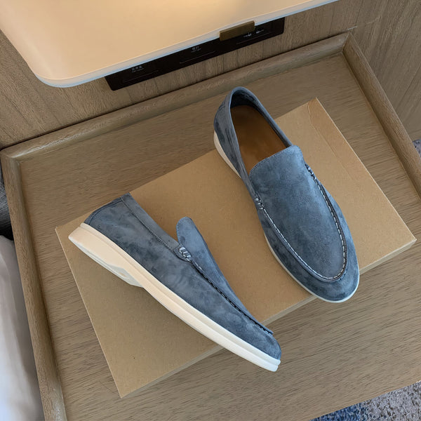 Blauwe suède loafers op kartonnen doos, stijlvolle herenschoenen met witte zolen, perfect voor casual en formele gelegenheden.