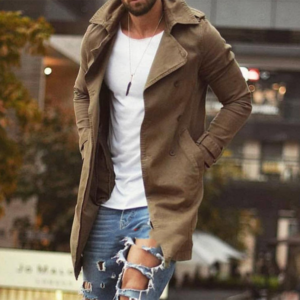 Man in een stijlvolle, lange, bruine jas voor heren, gecombineerd met een wit T-shirt en gescheurde jeans. Perfecte herfstmode voor mannen.