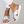 Zilveren damesslippers met kruisbanden en witte zool, gedragen door vrouw in witte broek. Comfortabele zomerschoenen, modieuze sandalen.