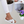Damesvoeten in witte comfortabele slippers met kruisbanden, naast een witte bloempot en tijdschriften. Perfect voor casual zomeroutfits.