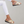 Gouden damesslippers met kruisbanden en zwarte zool, gedragen door model in witte broek. Comfortabele zomerschoenen voor dagelijks gebruik.